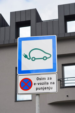 A blue electric vehicle icon sign with a secondary panel in Croatian indicating a parking restriction except for charging e vehicles - osim za e-vozila na punjenju