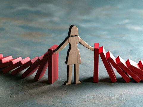 Cutout wooden figure of a business woman with her arms outstretched stopping wooden dominos falling on her from both sides