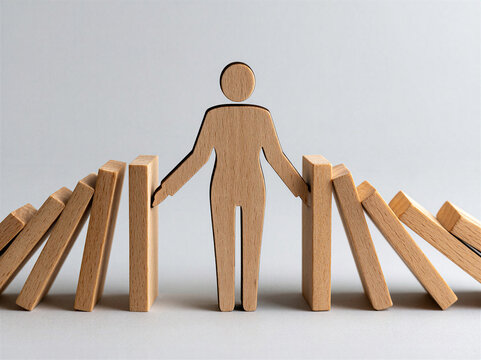 Cutout wooden figure of a business woman with her arms outstretched stopping wooden dominos falling on her from both sides