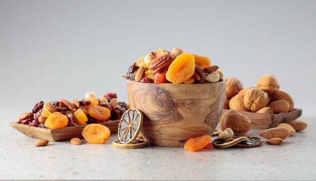 Assorted nuts and dried fruits in wooden dish.