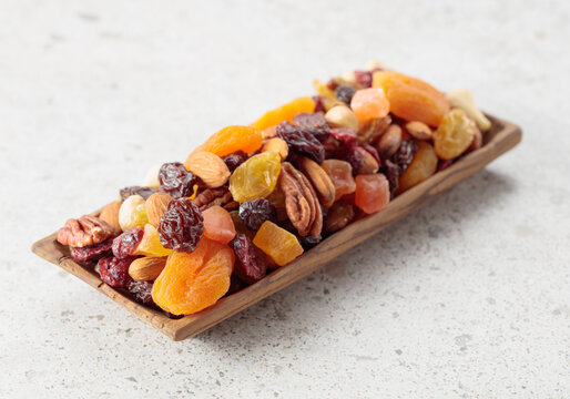 Assorted nuts and dried fruits in wooden dish.
