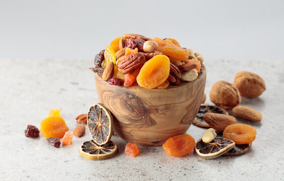 Assorted nuts and dried fruits in wooden dish.