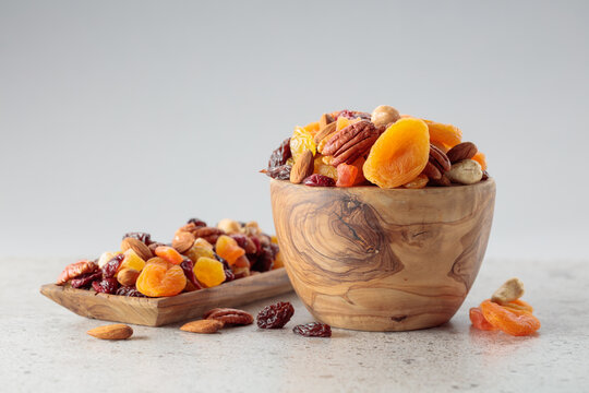 Assorted nuts and dried fruits in wooden dish.
