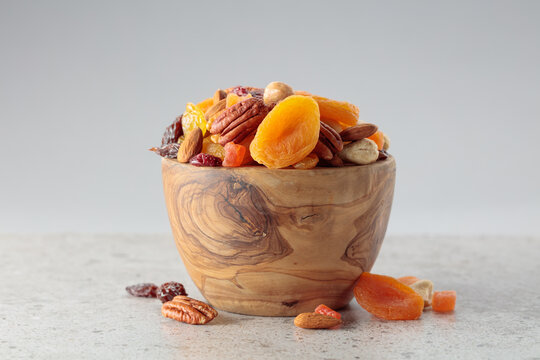 Assorted nuts and dried fruits in wooden dish.