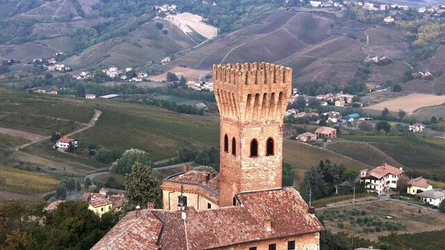 Castello di Cigognola aerial view descending reveal, medieval castle tower and autumn vineyards, Cigognola, Pavia, Lombardy, Italy