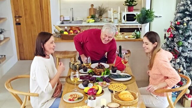 Three family members arrange a festive holiday meal around a dining table in a bright home kitchen