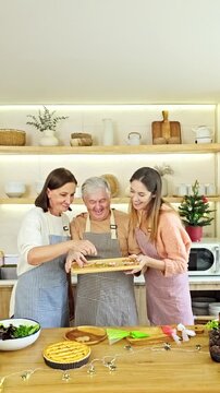 Three generations decorate holiday treats together in a bright home kitchen