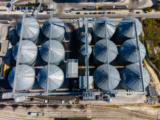 Aerial view of grain silos and conveyor equipment at an industrial storage facility during daytime © DSMT