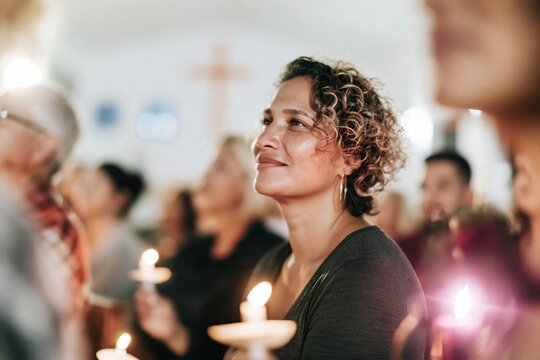 Diverse parishioners holding glowing candles during a solemn Advent service in a white church for faith and spirituality