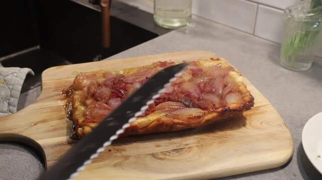 Stockholm, Sweden. A home cook reveals a steamy, hot upside-down shallot-onion tart, or Shallot Tatin, on a wooden board. 
