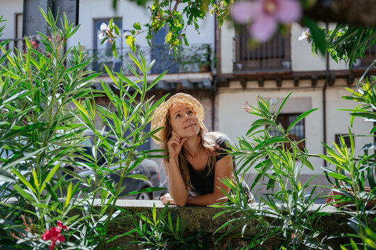 Thoughtful Middle Aged European Beauty in Straw Hat Enjoying a Hot Summer Day in Spanish Village