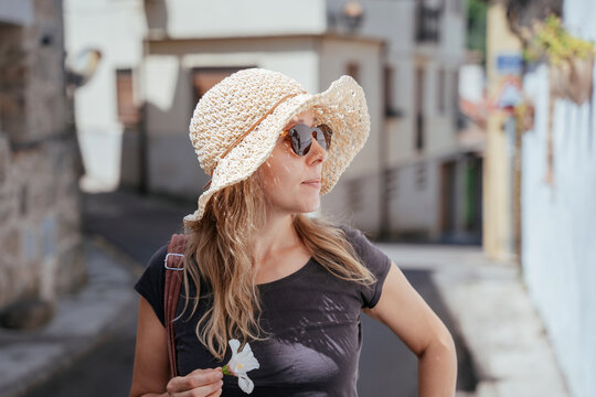 Thoughtful European Female Over 40 Holding White Flower on a Sunny Street in Spain