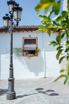 Traditional Spanish Village Architecture with Ornate Street Lantern and Sharp Midday Shadows