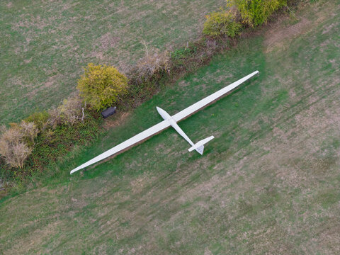 White Glider Parked on Green Grass Next to Trees From Above View