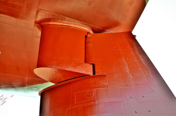 Close-up of a massive merchant ship rudder where it connects to the hull, photographed in dry dock after repair work. © Mariusz