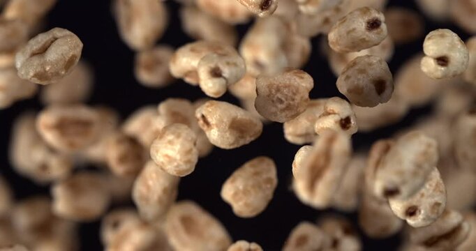 Puffed wheat cereal falling in slow motion 1000 fps on black background
