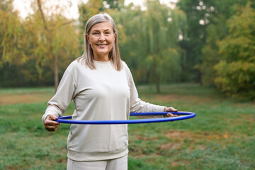 Senior woman exercising with hula hoop outdoors © New Africa