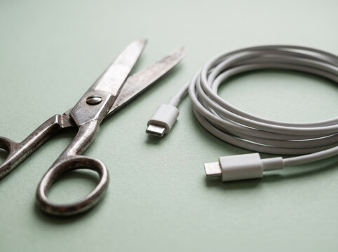 Old Metal Scissors Cutting Through White Charging Power Cable