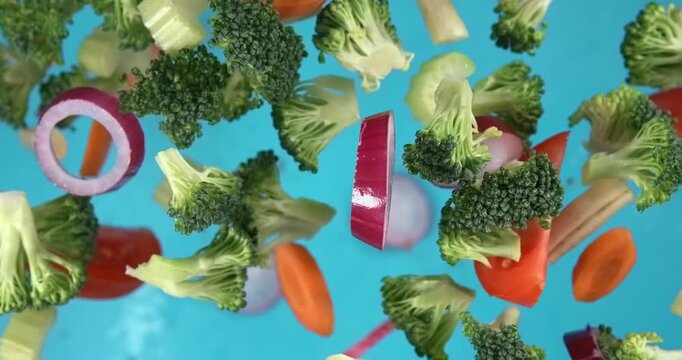Mixed vegetables falling in slow motion 1000 fps on blue background