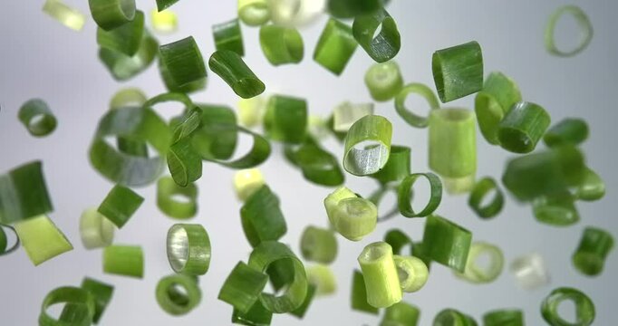 Green onion slices falling in slow motion 1000 fps on white background