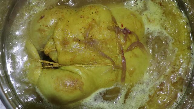Top view of whole chicken simmering in saffron broth