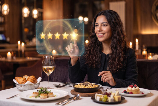 Mulher brasileira sorrindo tocando cinco estrelas em tela hologr&aacute;fica futurista durante jantar em restaurante aconchegante, mostrando conceito de qualidade no atendimento e avalia&ccedil;&atilde;o do cliente