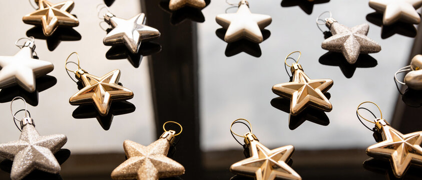 White and gold star-shaped ornaments hanging above a bright white copy space background