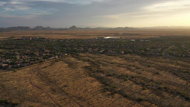 Aerial view of desert landscape with mountains and suburban homes at sunset