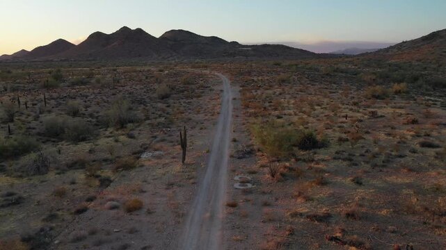 Aerial view of a dirt road winding through a desert landscape at sunset