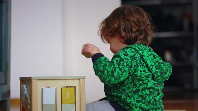 Curious Caucasian toddler playing with a wooden shape sorter toy