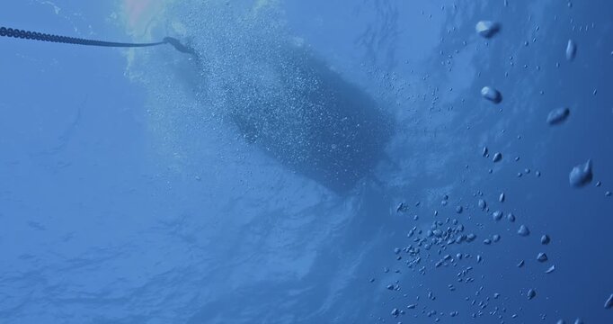 Scuba diver holding on to anchor line in heavy current.