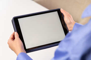 Tablet mock up with blank white screen held by person in blue shirt indoors. white screen device isolated screen communication empty space frame mockup, internet touchpad inform © Kateryna Muzhevska