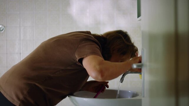Elderly Caucasian woman washing her face and drying it with a towel