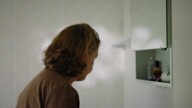 Caucasian senior woman applying moisturizer to her face and neck
