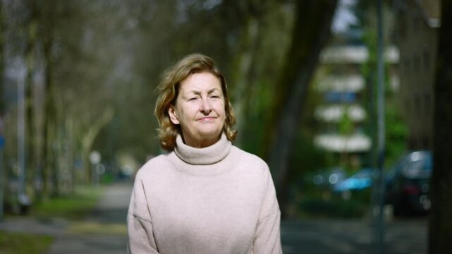Caucasian senior lady walking toward the camera on a park path