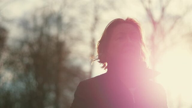 Caucasian older woman glowing in bright sunlight with wind in her hair
