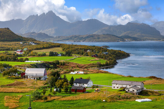 Scenic Lofoten coastline with farms, green fields, fjord and dramatic mountains in Norway