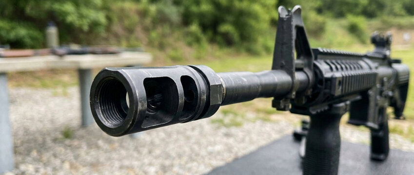 Close up of rifle muzzle brake on shooting range with blurred background