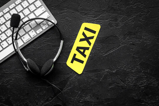 Call taxi online. Taxi label, keyboard, headphones on black background top view copyspace