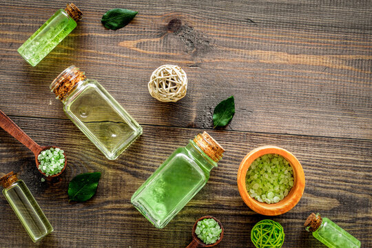 Organic cosmetics with tea tree oil and spa salt on dark wooden background top view copyspace
