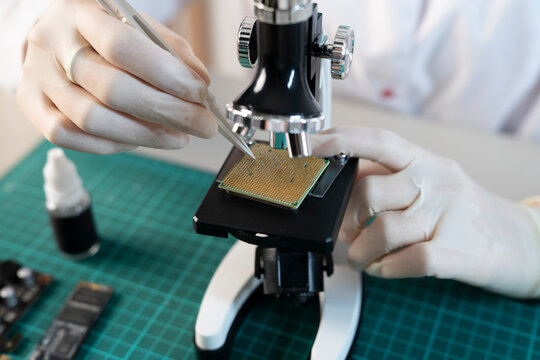 Detailed inspection of golden CPU processor contact pins under optical microscope using fine precision tweezers
