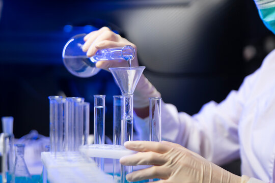 Close Up Of Vaccine Liquid Being Poured Into Test Tubes Through Funnel During Lab Research
