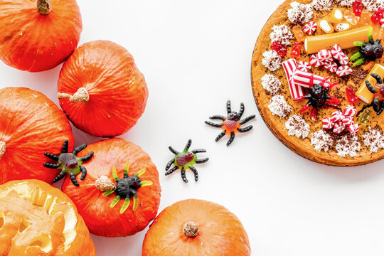 Halloween tradition. Pumpkin pie and pumpkin with scary face on white background top view