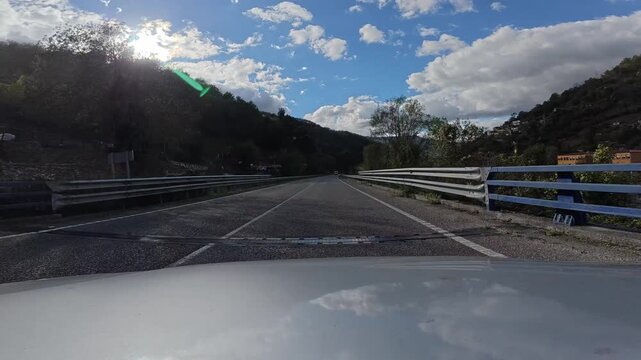 Car driving down the scenic mountain road of san isidro port through aller valley in asturias, showcasing rural landscapes under cloudy sky