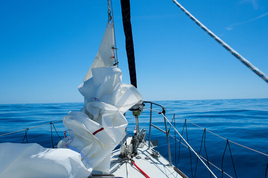 Sailing in Greece in the summer, View from the front of a yacht showing distant islands and the fore sail