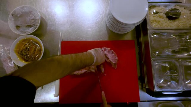 Hands Slice Raw Meat on a Red Cutting Board in a Kitchen