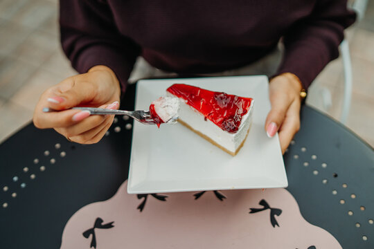 Woman lifting a forkful of cherry cheesecake at a cafe