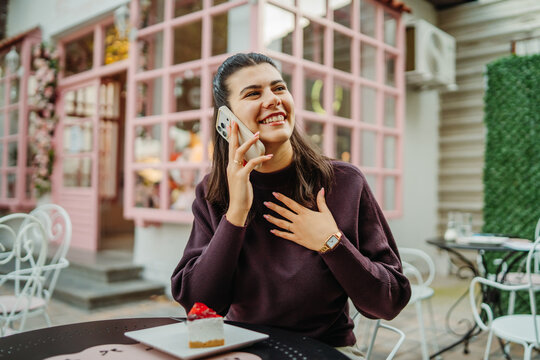 Smiling woman talking on smartphone at an outdoor cafe