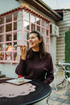 Woman laughing into smartphone during an outdoor cafe break
