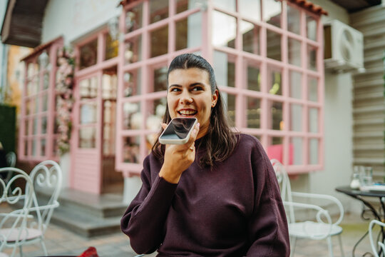 Woman recording a voice message at an outdoor cafe